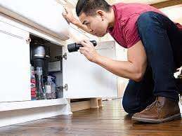 Intervenant en extermination de parasites effectuant un traitement sous un évier pour éliminer les insectes et rongeurs.